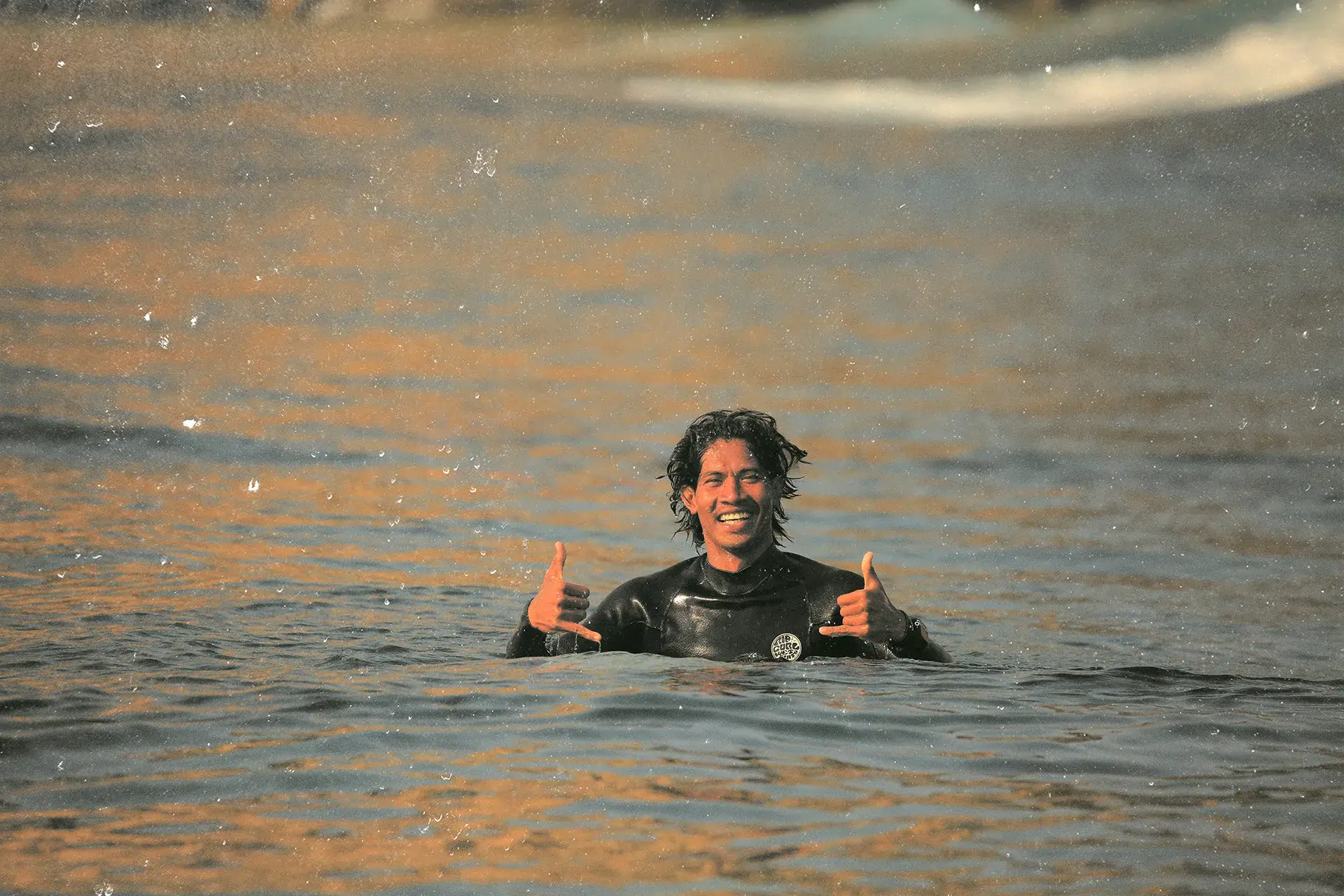 Calon in the water, smiling, in the warm 90s surf-magazine treatment